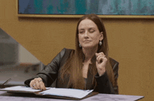 a woman sits at a desk with a clipboard and papers