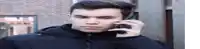 a young man is talking on a cell phone while wearing a black jacket .