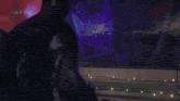 a person is standing in a dark room with a purple light shining on them