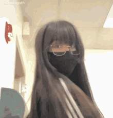 a girl with long hair and glasses is wearing a black mask .
