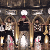 a group of young men are dancing in front of a wall with a clock on it