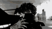 a black and white photo of a man with dreadlocks wearing a black mask .
