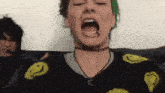a woman with green hair is wearing a black sweater with yellow smiley faces