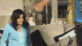 a woman in a blue shirt is standing in front of a couch