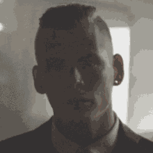 a man in a suit and tie is standing in a dark room looking at the camera .