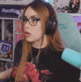 a woman wearing glasses and headphones sits in front of a renrize sign