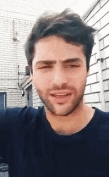 a man with a beard wearing a black shirt is smiling and looking at the camera .