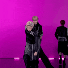 two men are dancing in front of a pink background .