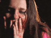 a woman with blood on her face covering her mouth with her hand