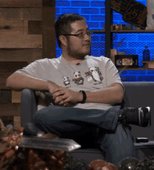 a man sitting on a couch wearing a shirt that says lvc 100