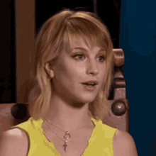 a close up of a woman wearing a yellow shirt and a necklace .
