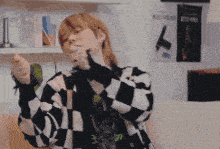 a woman wearing a black and white checkered sweater is dancing