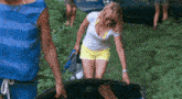 a woman in a white shirt and yellow shorts holds a canoe