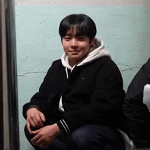 a young man wearing a black jacket and a white hoodie