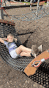 a young boy is laying in a hammock in a playground .