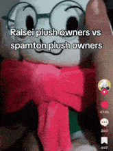 a stuffed animal wearing glasses and a pink scarf is being held by a person