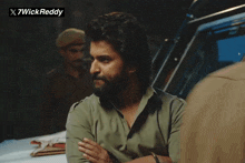 a man with a beard is standing in front of a sign that says x7wickreddy