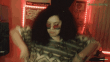 a woman dancing in front of a happy halloween sign