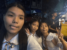 three girls pose for a picture in front of a yellow container that says ' ice cream '