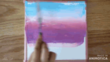a person is painting a purple and blue landscape on a canvas .