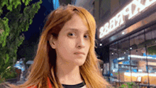 a woman with long red hair is standing in front of a building that says burger king