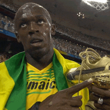 a man wearing a jamaica shirt is holding a pair of gold shoes