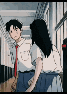a boy and a girl are walking down a hallway holding hands .