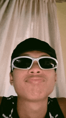 a young man wearing sunglasses and a hat is making a funny face