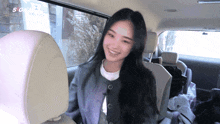 a woman sits in the back seat of a car with a sign that says sg