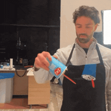 a man wearing an apron is pouring a drink into a cup that says dq on it