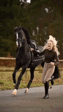 a woman is running behind a black horse