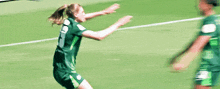 two female soccer players are hugging each other on a soccer field .