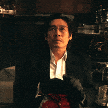 a man in a black suit and white shirt has blood on his shirt