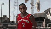 a man wearing a red raptors jersey with the number 2 on the front