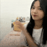 a girl in a white shirt is sitting on a bed and looking at the camera .