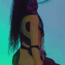 a woman in a yellow dress is dancing in front of a neon heart sign .
