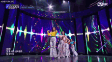 a group of women are dancing on a stage in front of a sign that says ' mnet ' on it