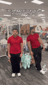 two men in red shirts are standing next to each other in a store