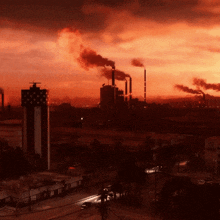 a factory with smoke coming out of the chimneys at night