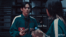 a man and a woman standing next to each other wearing netflix jackets