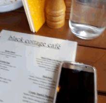 a menu for the black orange cafe is on a table next to a cell phone