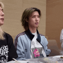 a man wearing a blue adidas jacket sits at a table with a woman