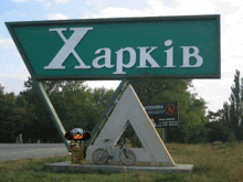 a large green sign that says " харків " with a bicycle in front of it