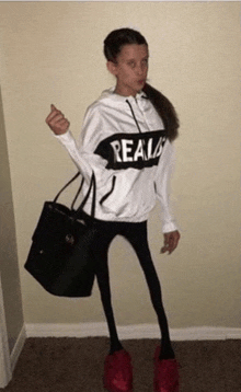 a girl wearing a white hoodie that says reals