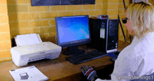 a woman sits at a desk with a canon printer