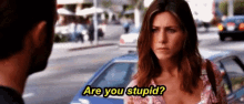 a woman is asking a man if he is stupid while standing in front of a blue car .