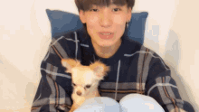 a man in a plaid shirt is holding a small dog in his lap