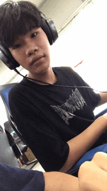 a young boy wearing headphones and a black shirt with the word assault on it