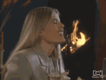 a woman is eating french fries in front of a fireplace with nuestra tele in the corner