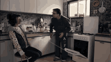 a man standing next to a woman in a kitchen wearing a pair of pants with the letter a on them